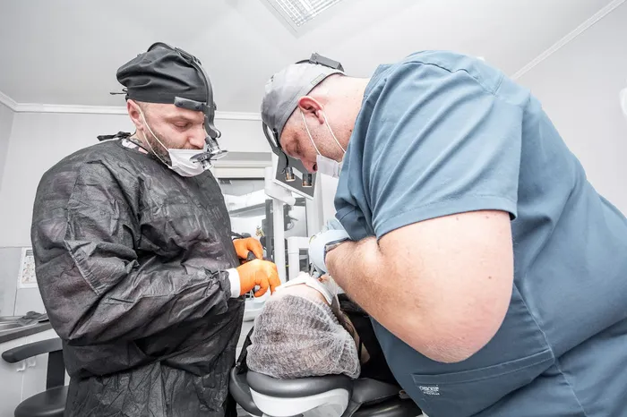 Two dental surgery professionals in sterile gowns and masks — the clinical team standard at internationally accredited Antalya dental clinics handling complex implant and surgical cases